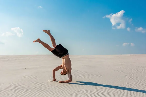 Junger Mann springt am Strand mit weißem Sand und strahlend blauem Himmel — Stockfoto