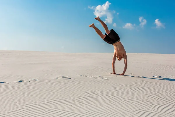 Sportlicher junger Mann will akrobatische Übungen auf dem Sand am Fluss machen — Stockfoto