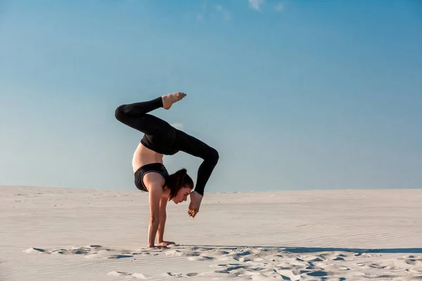 Junge Frau übt Handstand am Strand mit weißem Sand und strahlend blauem Himmel — Stockfoto