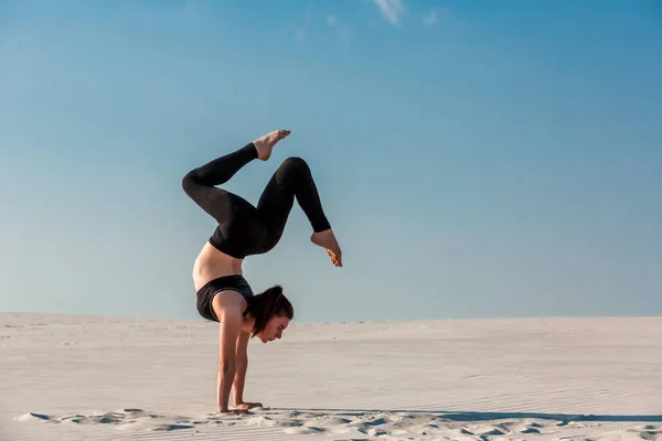 Junge Frau übt Handstand am Strand mit weißem Sand und strahlend blauem Himmel — Stockfoto