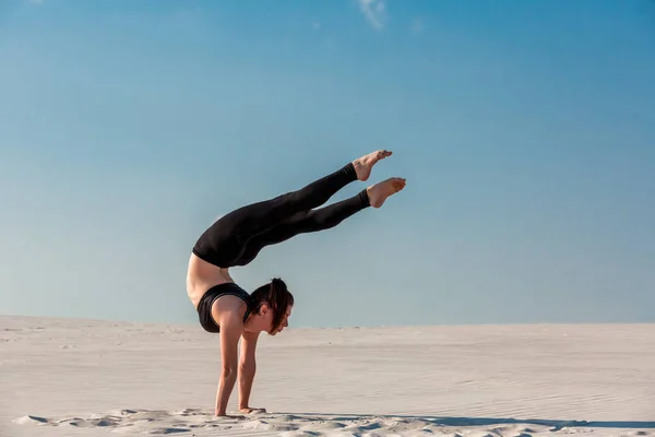 Junge Frau übt Handstand am Strand mit weißem Sand und strahlend blauem Himmel — Stockfoto