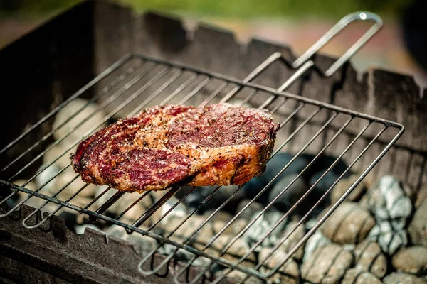 Grillade de steak épicé chaud sur un barbecue d'été sur les charbons chauds garnis . — Photo