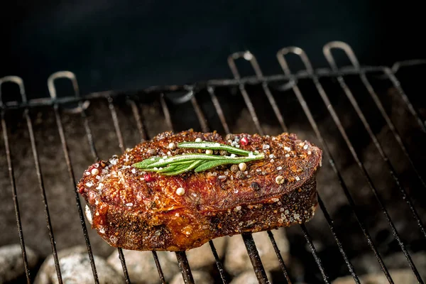 Bife picante quente grelhando em um churrasco de verão sobre as brasas quentes decoradas com um ramo de alecrim — Fotografia de Stock