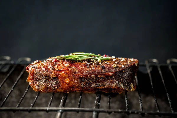Hot spicy steak grilling on a summer barbecue over the hot coals garnished decorated with a branch of rosemary — Stock Photo, Image
