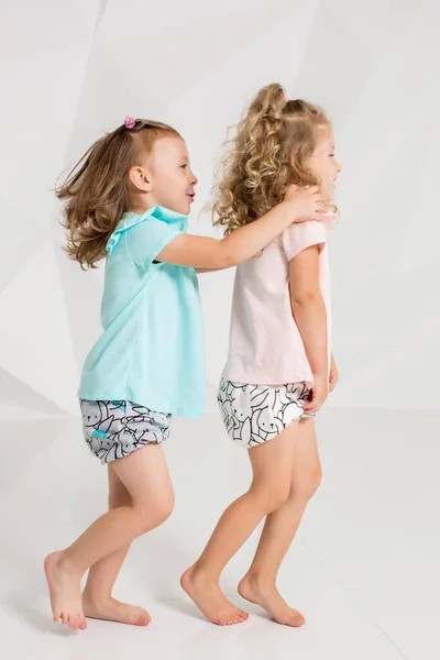 Két kis vicces, és nevetve a lány az azonos ruhát a különböző színek a fehér stúdió játék — Stock Fotó