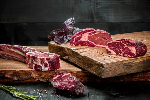 Čerstvé syrové hovězí maso na prkénku s čerstvou bazalkou a rozmarýnem — Stock fotografie