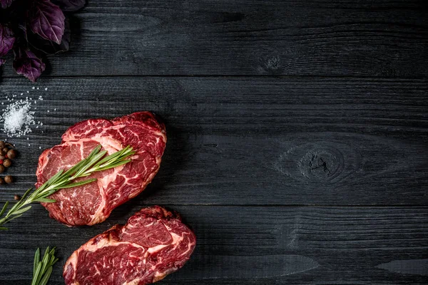 Taze çiğ et fesleğen ve biberiye siyah ahşap zemin üzerine bir delikanlı ile