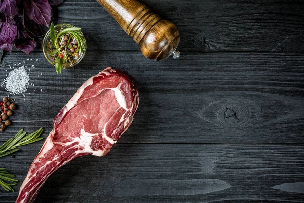 Taze çiğ et fesleğen ve biberiye siyah ahşap zemin üzerine bir delikanlı ile