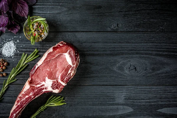 Taze çiğ et fesleğen ve biberiye siyah ahşap zemin üzerine bir delikanlı ile