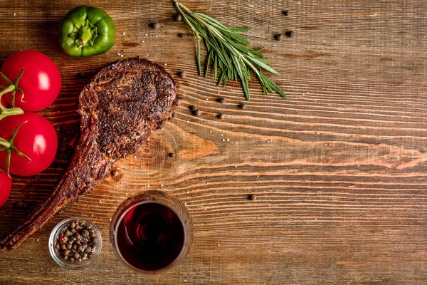 Churrasco costela envelhecida seca de carne bovina com legumes e copo de vinho tinto close-up em fundo de madeira — Fotografia de Stock