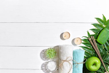 Spa Ürünleri. Banyo tuzları, sabun, mumlar ve havlu. Düz beyaz ahşap zemin, üstten görünüm üzerinde yatıyordu.