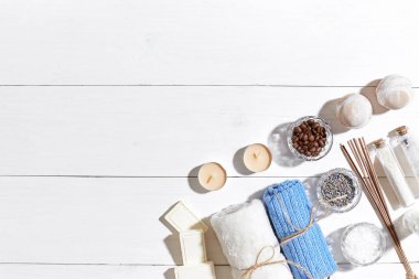 Spa Ürünleri. Banyo tuzları, kuru çiçekler lavanta, sabun, mumlar ve havlu. Düz beyaz ahşap zemin, üstten görünüm üzerinde yatıyordu.