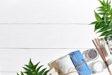 Spa Ürünleri. Banyo tuzları, kuru çiçekler lavanta, sabun, mumlar ve havlu. Düz beyaz ahşap zemin, üstten görünüm üzerinde yatıyordu.