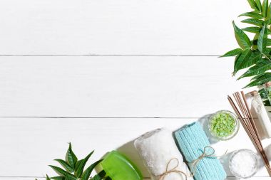 Spa Ürünleri. Banyo tuzları, sabun, mumlar ve havlu. Düz beyaz ahşap zemin, üstten görünüm üzerinde yatıyordu.