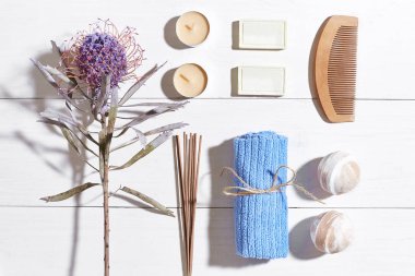 Spa Ürünleri. Banyo tuzları, kuru çiçekler lavanta, sabun, mumlar ve havlu. Düz beyaz ahşap zemin, üstten görünüm üzerinde yatıyordu.