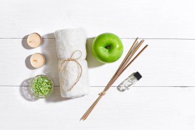 Spa Ürünleri. Banyo tuzları, sabun, mumlar ve havlu. Düz beyaz ahşap zemin, üstten görünüm üzerinde yatıyordu.