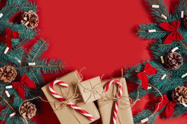 Çam kozalakları, çam dalları ve hediye kutuları kırmızı zemin üzerine yığını Noel bileşimi