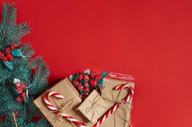 Çam kozalakları, çam dalları ve hediye kutuları kırmızı zemin üzerine yığını Noel bileşimi