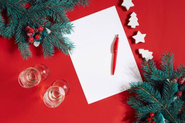 Kırmızı kalem ve kırmızı masa üstünde not etmek bir köknar dalı ile dekore edilmiştir. Metin için arka plan.