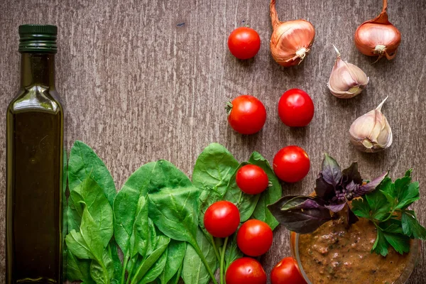 Ingredienti biologici freschi per la preparazione della salsa: spinaci, pomodori, germogli, basilico, olio d'oliva su fondo rustico, vista dall'alto . — Foto Stock