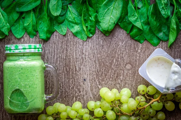 Ispanaklı karşı bir kupa ahşap arka plan üzerinde sağlıklı yeşil smoothie