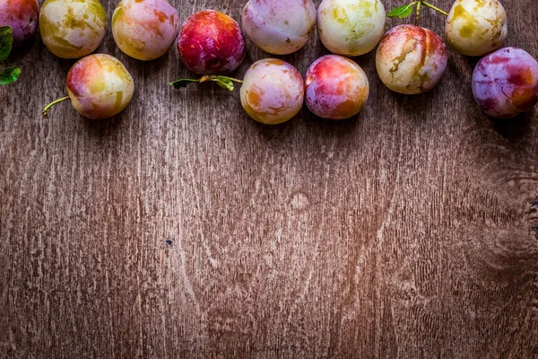 Ciruelas jugosas frescas sobre un fondo de madera — Foto de Stock