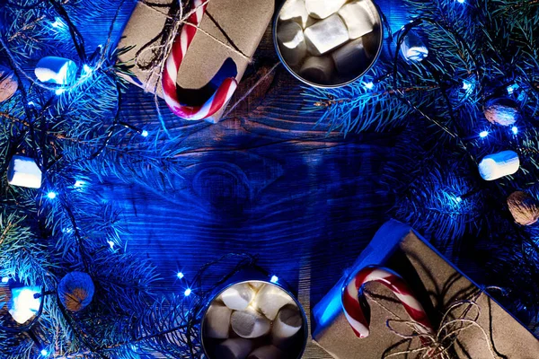 Christmas hot drink. Cocoa with marshmallow, garland and spruce branches on a wooden background. Top view — Stock Photo, Image