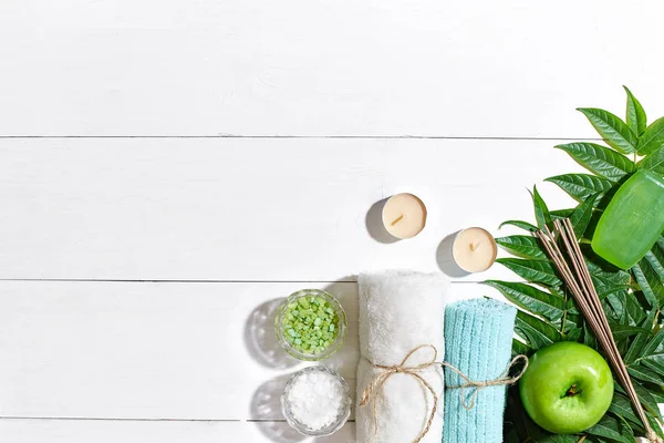 Spa Ürünleri. Banyo tuzları, sabun, mumlar ve havlu. Düz beyaz ahşap zemin, üstten görünüm üzerinde yatıyordu.