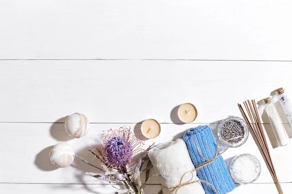 Spa products. Bath salts, dry flowers lavender, soap, candles and towel. Flat lay on white wooden background, top view. — Stock Photo, Image