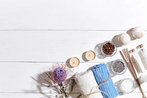 Spa products. Bath salts, dry flowers lavender, soap, candles and towel. Flat lay on white wooden background, top view. — Stock Photo, Image