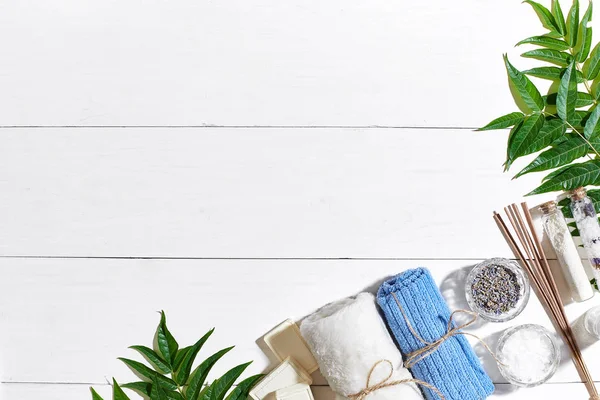 Spa Ürünleri. Banyo tuzları, kuru çiçekler lavanta, sabun, mumlar ve havlu. Düz beyaz ahşap zemin, üstten görünüm üzerinde yatıyordu.