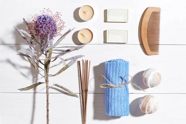 Spa Ürünleri. Banyo tuzları, kuru çiçekler lavanta, sabun, mumlar ve havlu. Düz beyaz ahşap zemin, üstten görünüm üzerinde yatıyordu.