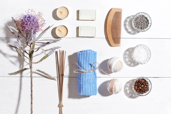 Spa Ürünleri. Banyo tuzları, kuru çiçekler lavanta, sabun, mumlar ve havlu. Düz beyaz ahşap zemin, üstten görünüm üzerinde yatıyordu.