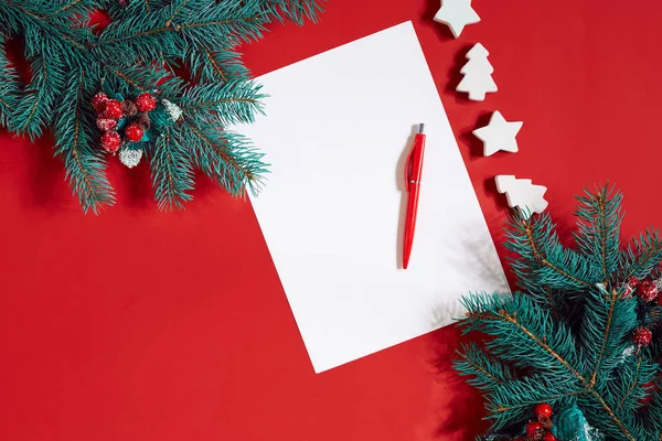 Kırmızı kalem ve kırmızı masa üstünde not etmek bir köknar dalı ile dekore edilmiştir. Metin için arka plan.