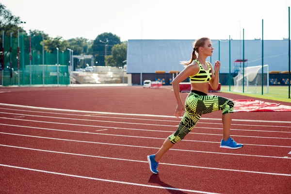 Vacker ung kvinna träning jogging och körs på athletic spår på stadion. — Stockfoto