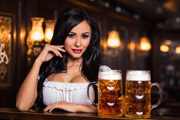Oktoberfest. Brünette Frau hält Bierkrüge in Bar — Stockfoto