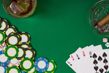 kumar, servet ve eğlence kavramı - casino fişi, viski cam, iskambil ve puro yeşil masa yüzeyi yakın