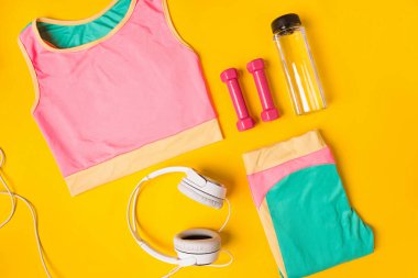 Spor donatımı ve giysileri ile sarı arka plan üstünde hareket eden telefon. Üstten Görünüm