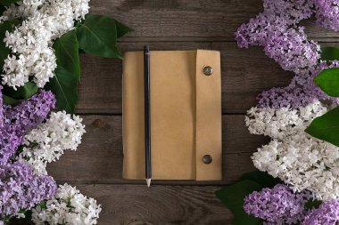 Leylak çiçeği mesaj tebrik için defter rustik ahşap zemin üzerine. Üstten Görünüm