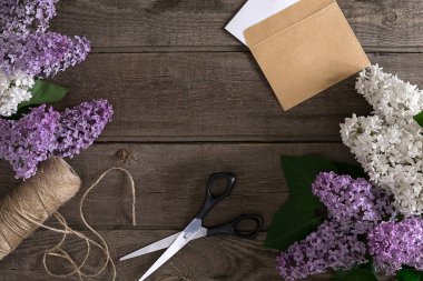 Leylak çiçeği mesaj tebrik için boş alanı rustik ahşap zemin üzerine. Makas, iplik makarası, küçük zarf. Üstten Görünüm