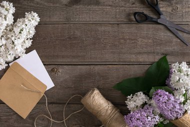 Leylak çiçeği mesaj tebrik için boş alanı rustik ahşap zemin üzerine. Makas, iplik makarası, küçük zarf. Üstten Görünüm