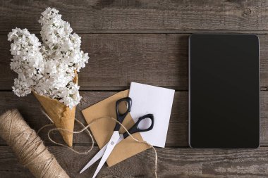 Leylak çiçeği tablet tebrik mesajı için boş alan ile rustik ahşap arka plan üzerinde. Makas, iplik makarası, küçük zarf. Üstten Görünüm