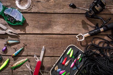 Fishing tackle - fishing spinning, fishing line, hooks and lures on wooden background. clipart
