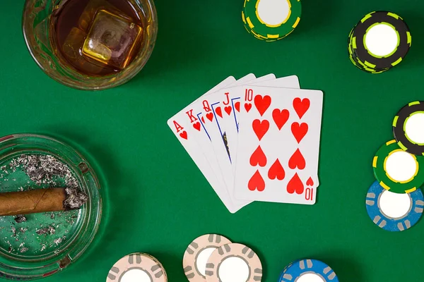 Concepto de juego, fortuna y entretenimiento: primer plano de fichas de casino, vaso de whisky, cartas y cigarros en la superficie de la mesa verde — Foto de Stock