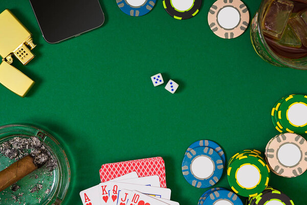 gambling, fortune and entertainment concept - close up of casino chips, whisky glass, playing cards and cigar on green table surface