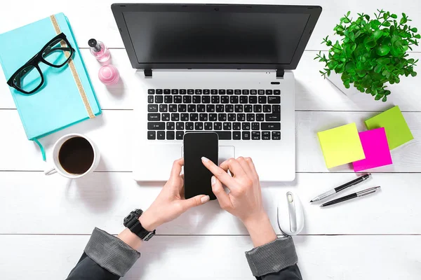 Computer portatile con schermo bianco e le mani delle ragazze. Posa piatta, spazio di lavoro con vista dall'alto — Foto Stock