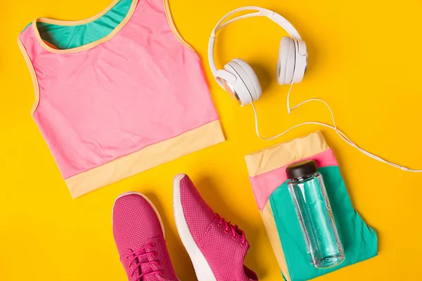 Spor donatımı. Spor ayakkabı ve şişe suyu Sarı zemin üzerine