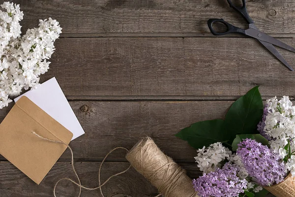 Leylak çiçeği mesaj tebrik için boş alanı rustik ahşap zemin üzerine. Makas, iplik makarası, küçük zarf. Üstten Görünüm
