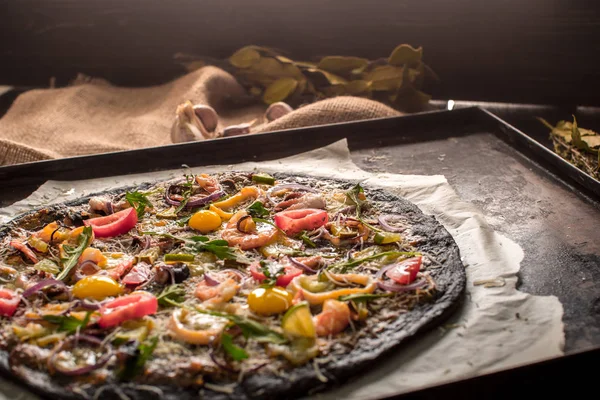 Italian pizza with black dough and seafood on a baking tray from the oven — Stock Photo, Image