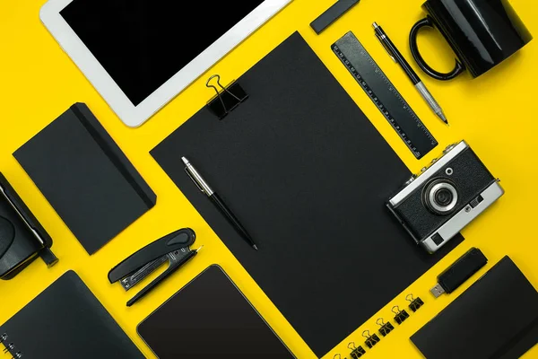 Schwarze Objekte aus dem Büro auf gelbem Hintergrund. Arbeit und Kreativität. Ansicht von oben. — Stockfoto
